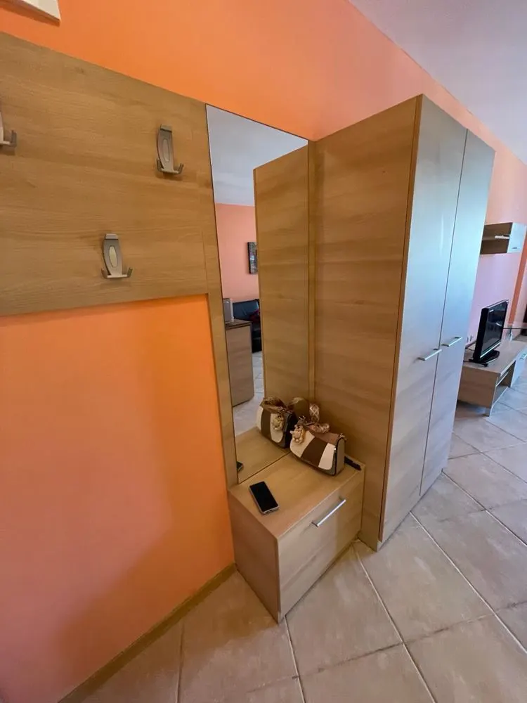 Entrance hallway with mirror, coat hooks, and shoe storage