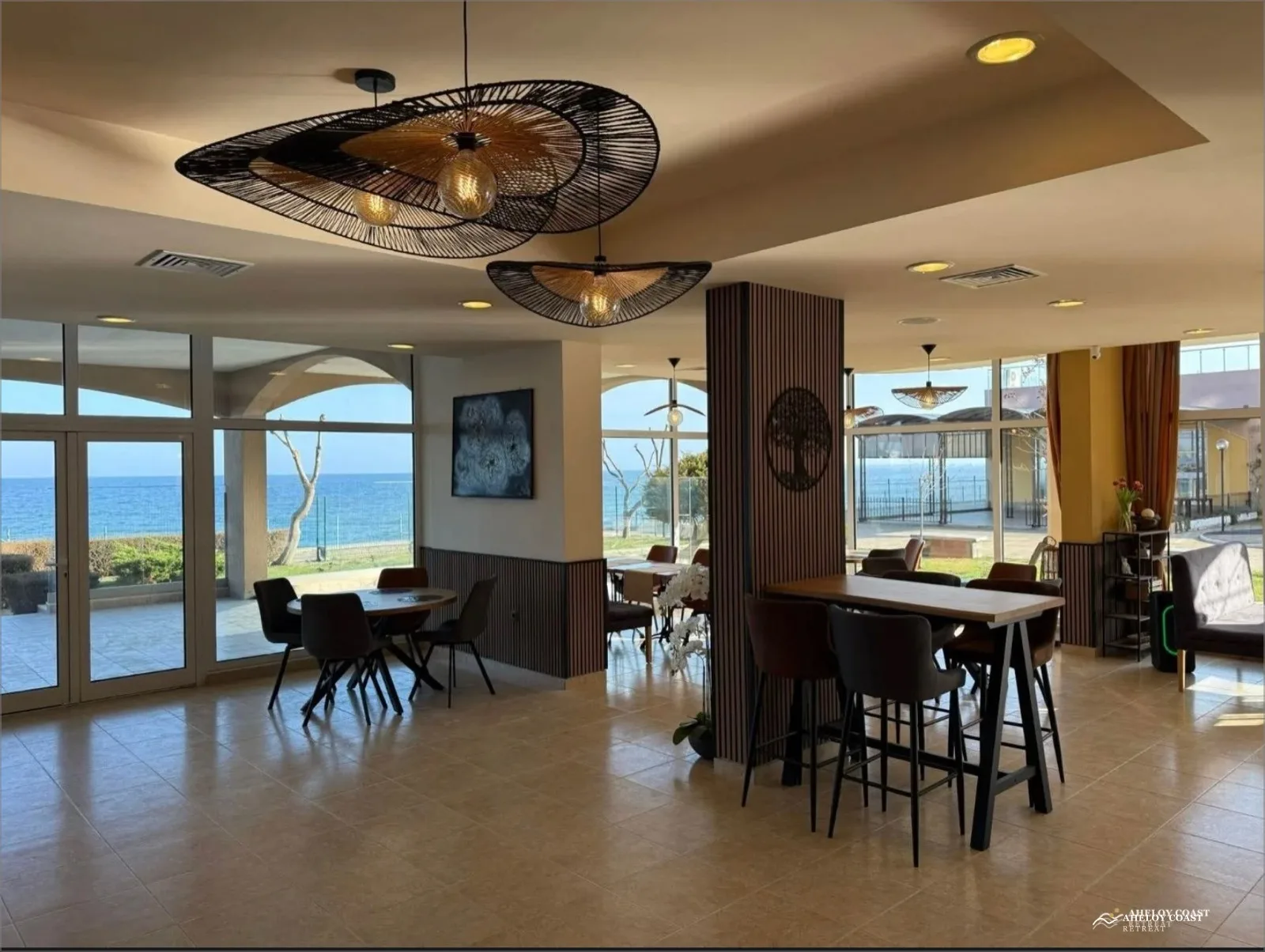 Modern sea-view restaurant at Midia Family Resort with pendant lighting, high tables, and floor-to-ceiling windows onto the Black Sea
