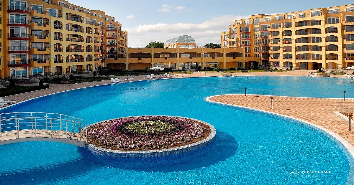 Smaller Midia Family Resort pool with a circular flower island, viewed from the first floor terrace of the on-site restaurant, with the reception building in the distance and the studio block on the right