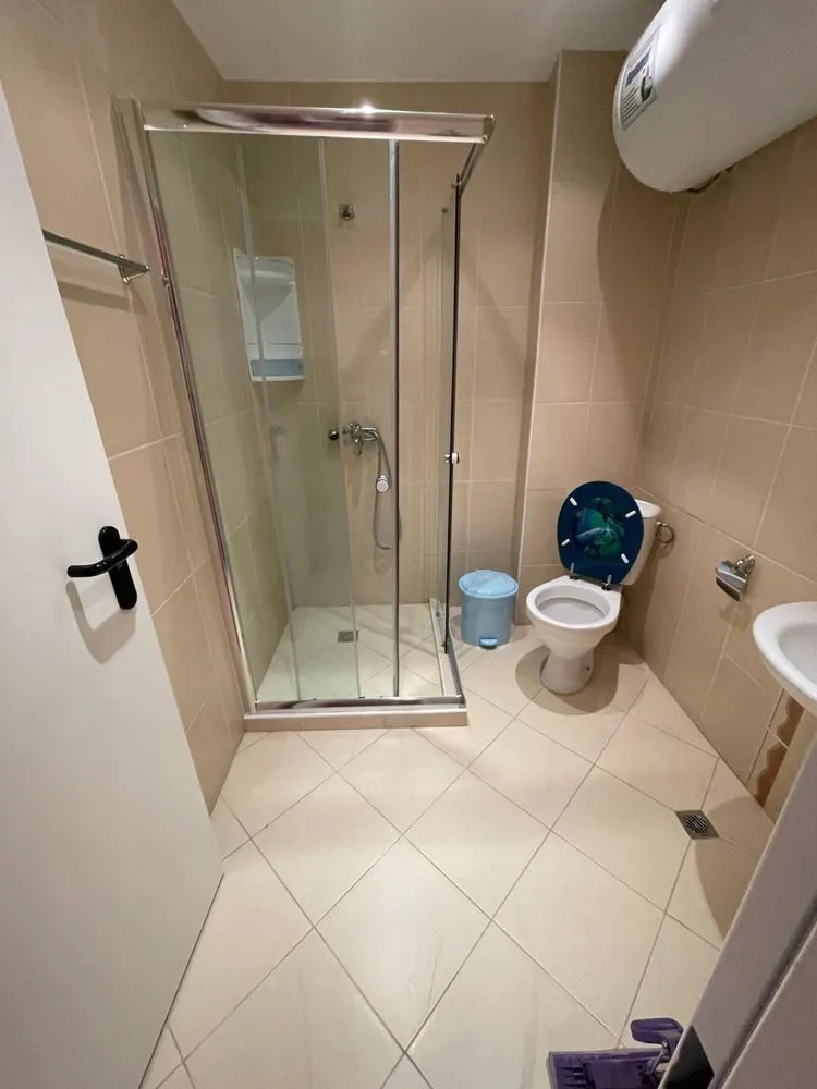 Bathroom with glass shower cabin, toilet, and water heater